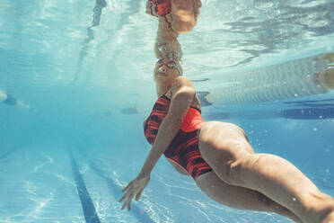 Unterwasseraufnahme einer Schwimmerin in Aktion im Schwimmbad. Fitte junge Schwimmerin beim Training im Schwimmbad. - JLPSF22893