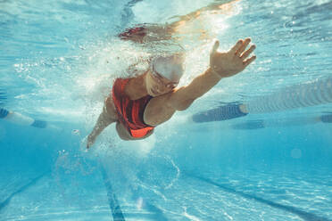 Underwater shot of female athlete swimming in pool. Young woman swimming the front crawl in a pool. - JLPSF22894