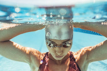 Unterwasseraufnahme einer Frau im Schwimmbad. Schwimmerin mit Badekappe und Schwimmbrille im Schwimmbad. - JLPSF22898