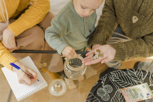 Parents with boy counting coins at home - VIVF00090