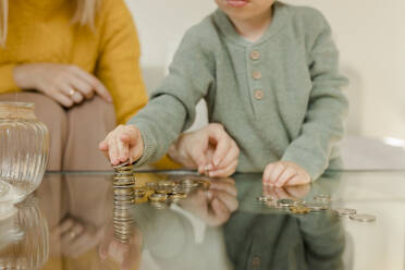 Mother with son counting coins on table at home - VIVF00097