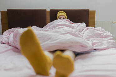 Junge Frau mit Decke entspannt auf dem Bett zu Hause - VIVF00125