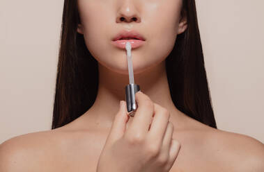 Close up of girl applying lip gloss. Cropped shot of woman applying lips makeup with cosmetic brush. - JLPSF22954