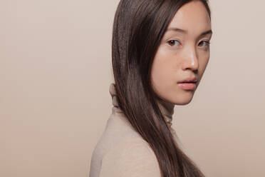 Porträt einer Frau mit glattem braunem Haar. Asiatische Frau mit langem Haar schaut in die Kamera. - JLPSF22964