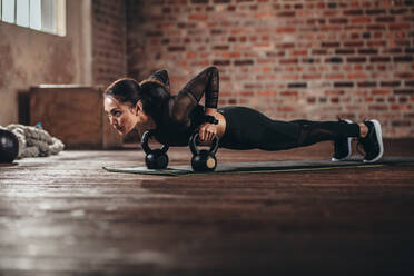 Junge Frau macht Push-up-Übungen auf einer Fitnessmatte in einem Fitnessstudio. - JLPSF23025