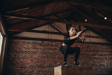 Fitte junge Frau bei einem Boxsacksprung. Sportliche Frau bei einem Boxsack im Fitnessstudio. - JLPSF23035