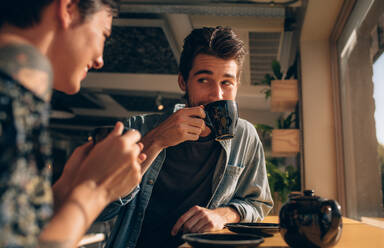 Junger Mann trinkt Kaffee mit seiner Freundin in einem Café. Paar trinkt zusammen Kaffee in einem Restaurant. - JLPSF23118