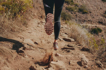 Frau Läufer Beine laufen auf Bergpfad. Füße der Frau Läuferin läuft über Steine auf Bergpfad. - JLPSF23156
