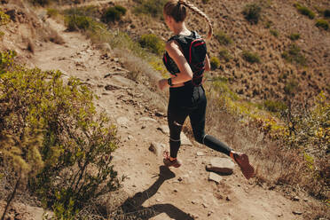 Top view of young woman running on mountain trail. Woman running on rocky trails on the hillside. - JLPSF23157