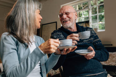 Alter Mann und Frau, die Zeit miteinander verbringen, sich unterhalten und Kaffee trinken. Älteres Paar, das zu Hause zusammensitzt und Kaffeetassen hält und sich gegenseitig ansieht. - JLPSF23211
