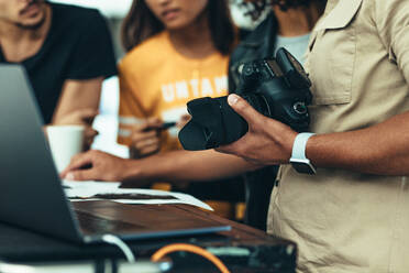 Fotograf bei der Nachbearbeitung eines Fotoshootings. Mann hält Kamera und bespricht Fotoshooting mit seinem Team. - JLPSF23238