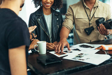 Photographer looking at photographs with model and his team. Photographer discussing about the photo shoot with his team. - JLPSF23240