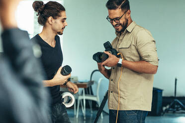 Photographer and camera assistant busy changing lenses during a fashion photo shoot. - JLPSF23259