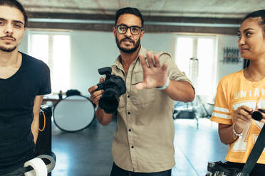 Photographer guiding a model about the pose during a photo shoot. Photographer with his assistants doing a photo shoot in a studio. - JLPSF23271