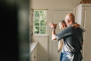 Glückliches älteres Paar, das zusammen tanzt und sich gegenseitig festhält. Romantisches älteres Paar, das Spaß beim Gesellschaftstanz zu Hause hat. - JLPSF23281