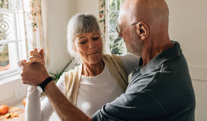 Senior couple dancing holding hands at home. Close up of an old man and woman having fun dancing at home. - JLPSF23288