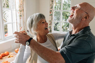 Älterer Mann und Frau tanzen fröhlich zu Hause. Glückliches älteres Paar, das Spaß an einem Gesellschaftstanz zu Hause hat. - JLPSF23289