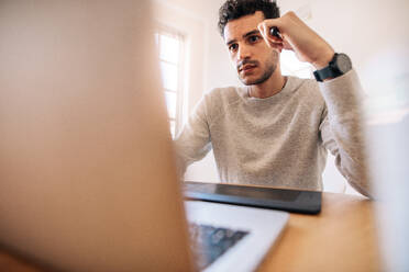 Businessman working on laptop computer with a digital writing pad in front. Entrepreneur looking at the laptop screen keenly holding a digital pen. - JLPSF23336