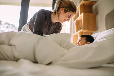 Young mother and her son playing together on the bed at home. Woman having fun with her son at home. - JLPSF23385