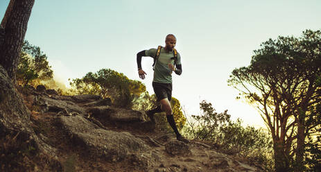 Mann, der auf einem Bergpfad läuft. Männliche Fitness, die durch einen felsigen Bergpfad läuft. - JLPSF23392