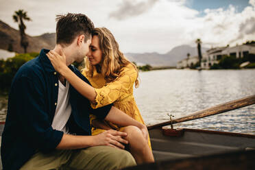 Verliebtes Paar sitzt zusammen in einem Boot und hält sich gegenseitig. Frau hält ihren Freund und berührt ihre Köpfe während eines Dates in einem Boot. - JLPSF23401
