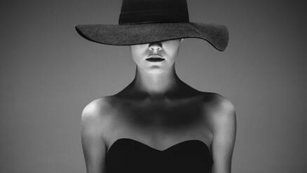 Beautiful elegant woman in a hat against grey background. Retro style black and white portrait of a sensual woman in a hat. - JLPSF23407