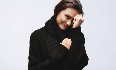 Porträt einer hübschen Frau, die in die Kamera schaut und lächelt. Weibliches Modell im schwarzen Pullover auf weißem Hintergrund. - JLPSF23424