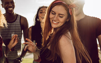 Beautiful woman dancing with friends around outdoors. Woman having a great time with group of friends on summer day. - JLPSF23530