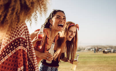 Drei junge Frauen, die zusammen im Freien spazieren gehen und lachen. Eine Gruppe multiethnischer Freundinnen hat Spaß im Freien. - JLPSF23535