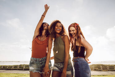 Group of three young women standing outdoors and dancing. Beautiful female friends having a great time on their summer vacation. - JLPSF23541