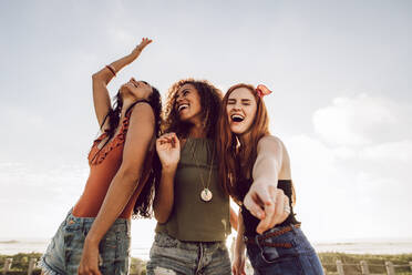 Group of diverse female friends dancing outdoors. Three women having a great time on their summer holidays. - JLPSF23542