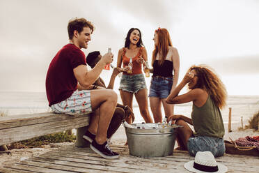 Eine Gruppe multiethnischer Freunde hängt am Strand ab und trinkt Bier. Männer und Frauen genießen ein Sommerwochenende am Strand. - JLPSF23548