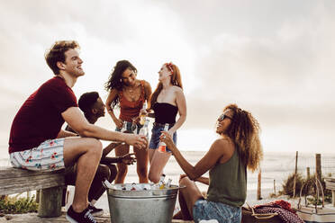 Eine Gruppe von Freunden, die mit einem Bier am Strand abhängen. Junge Leute, die sich mit einem Bier im Freien vergnügen. - JLPSF23549