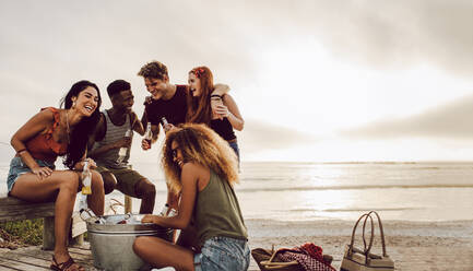 Gruppe multiethnischer Freunde, die gemeinsam ein Bier am Strand trinken. Gruppe von Männern und Frauen, die am Meer Bier trinken. - JLPSF23553