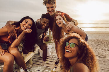 Young woman talking selfie with diverse group of friends at the beach. Multiracial young men and women posing for a selfie. - JLPSF23556