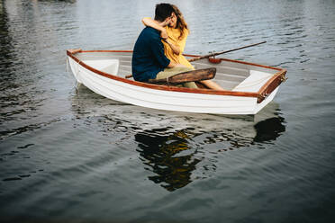 Junges Paar bei einer Verabredung in einem Boot sitzend und sich gegenseitig haltend. Frau küsst ihren Freund und hält ihn in den Armen während einer Verabredung in einem Boot. - JLPSF23583