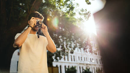 Mann beim Fotografieren mit einer Kamera mit Sonne im Hintergrund. - JLPSF23621