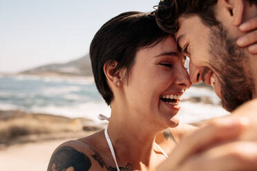 Mann und Frau stehen eng beieinander und berühren sich am Strand. Ein Touristenpaar in glücklicher und romantischer Stimmung genießt seinen Urlaub. - JLPSF23625