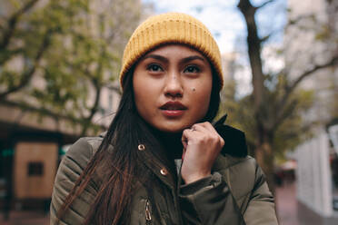 Porträt einer Frau in Winterkleidung, die auf der Straße steht. Asiatische Frau, die an einem kalten Morgen in Winterkleidung im Freien steht. - JLPSF23673