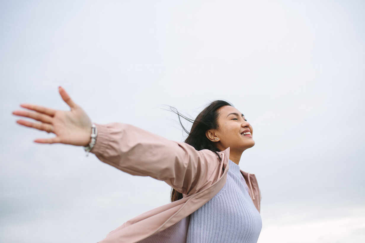 Side view of a woman standing outdoors with stretched arms and