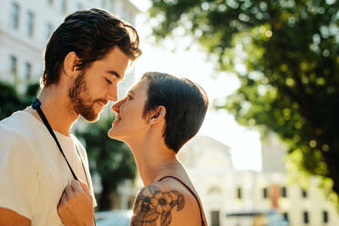 Frau, die in der Nähe eines Mannes steht, der gerade dabei ist, sich auf der Straße zu küssen. Ein Touristenpaar in einer glücklichen und romantischen Stimmung, während es die Stadt erkundet. - JLPSF23722