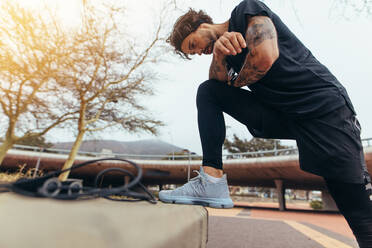 Mann, der sich nach einem morgendlichen Lauf im Freien ausruht. Sportler, der eine Pause vom Lauftraining im Freien macht. - JLPSF23760