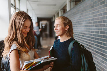 Zwei Universitätsstudenten stehen nach dem Unterricht im Flur und unterhalten sich. Zwei Studentinnen nach der Vorlesung. - JLPSF23780