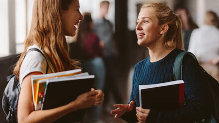 Lächelnde Mädchen auf dem Schulflur, zwei Studentinnen im Gespräch nach einer Vorlesung. - JLPSF23781