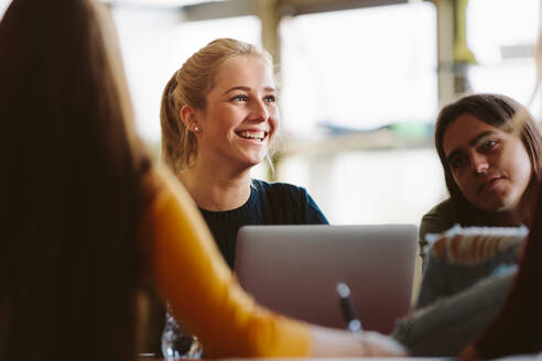 Eine Studentin sitzt im Hörsaal zwischen ihren Mitschülern und lächelt. Universitätsstudenten im Klassenzimmer nach der Vorlesung. - JLPSF23803