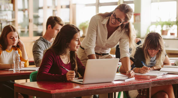 Smiling female lecturer helping student during her class. Student in a lecture with helpful teacher. - JLPSF23812