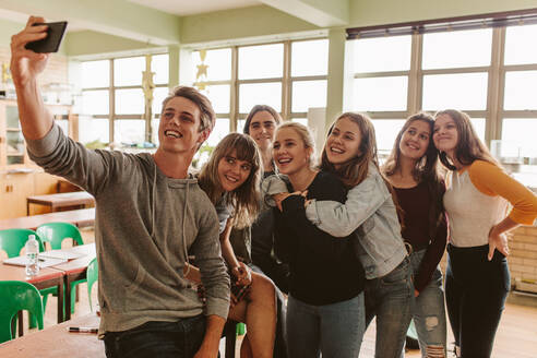 Gruppe von Universitätsstudenten, die ein Selfie mit einem Smartphone im Klassenzimmer machen. Junge Leute im Hörsaal, die ein Selfie mit einem Mobiltelefon machen. - JLPSF23831