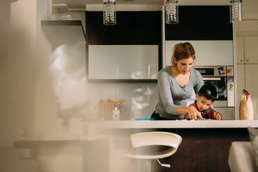 Mutter bringt ihrem Sohn das Plätzchenbacken bei. Frau mit ihrem Sohn beim Plätzchenbacken in der heimischen Küche. - JLPSF23863