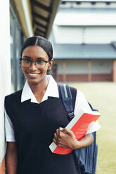 Smiling female student walking through school hallway looking at camera and smiling. School girl going for the class. - JLPSF23882