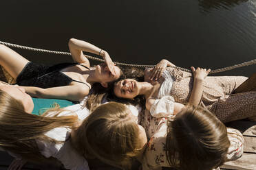 Smiling young women lying on friends lap - LLUF00900